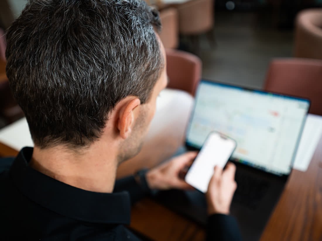 Philipp Kozalla analysiert Charts am Laptop und auf dem Smartphone